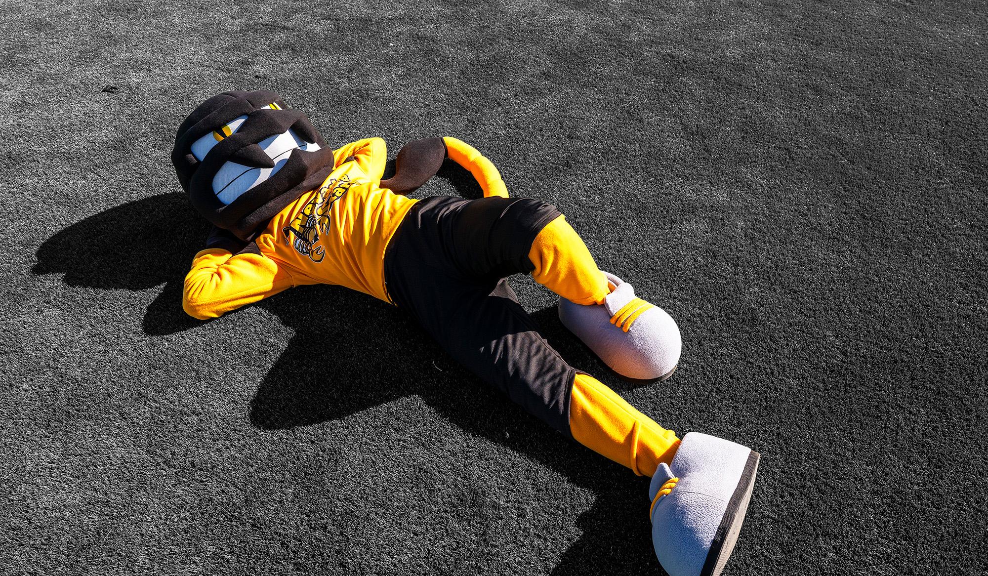 Nevada State Scorpions mascot posing on black background, showcasing the gold uniform and distinctive scorpion mask